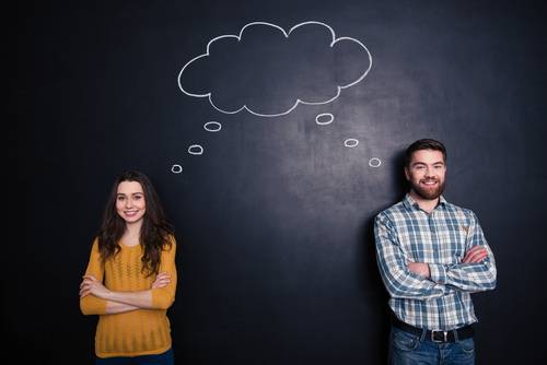 man and woman sharing ideas against a chalkboard