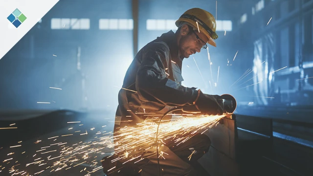 Industrial manufacturing worker using angle grinder to cut metal tube